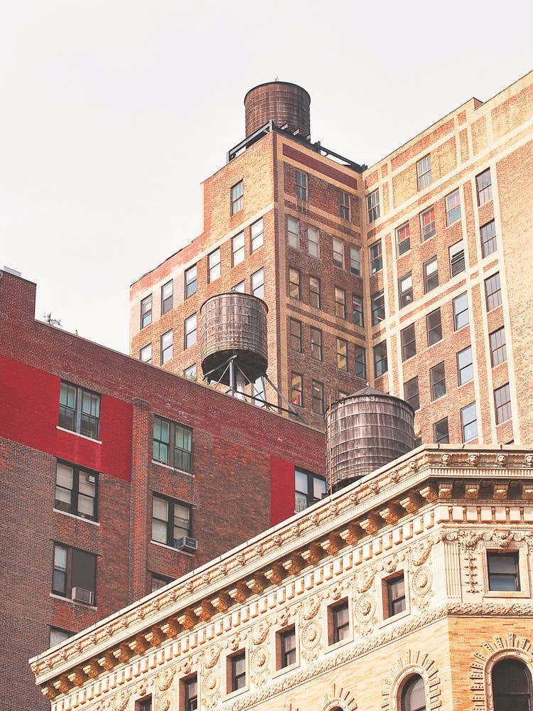 New York, USA I Roofs with water tanks in skyline with its minimalist industrial red brick new yorker loft architecture in a red aesthetic with the retro vintage style of old film photography