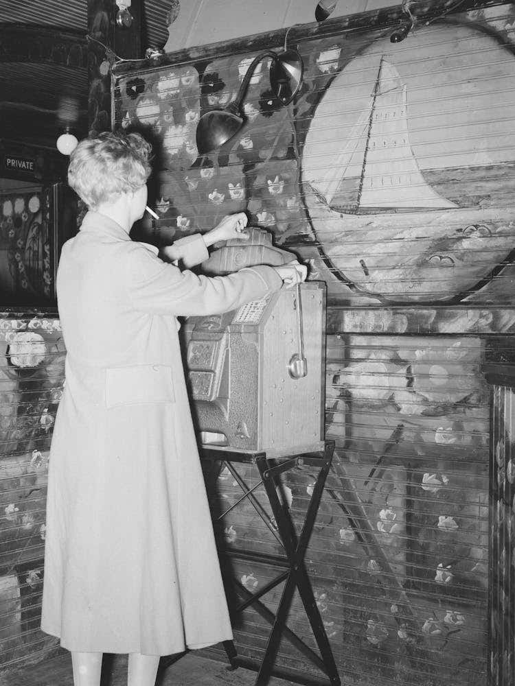 Girl Playing Slot Machine In Decorated Barroom, Raceland, Louisiana By Russell Lee