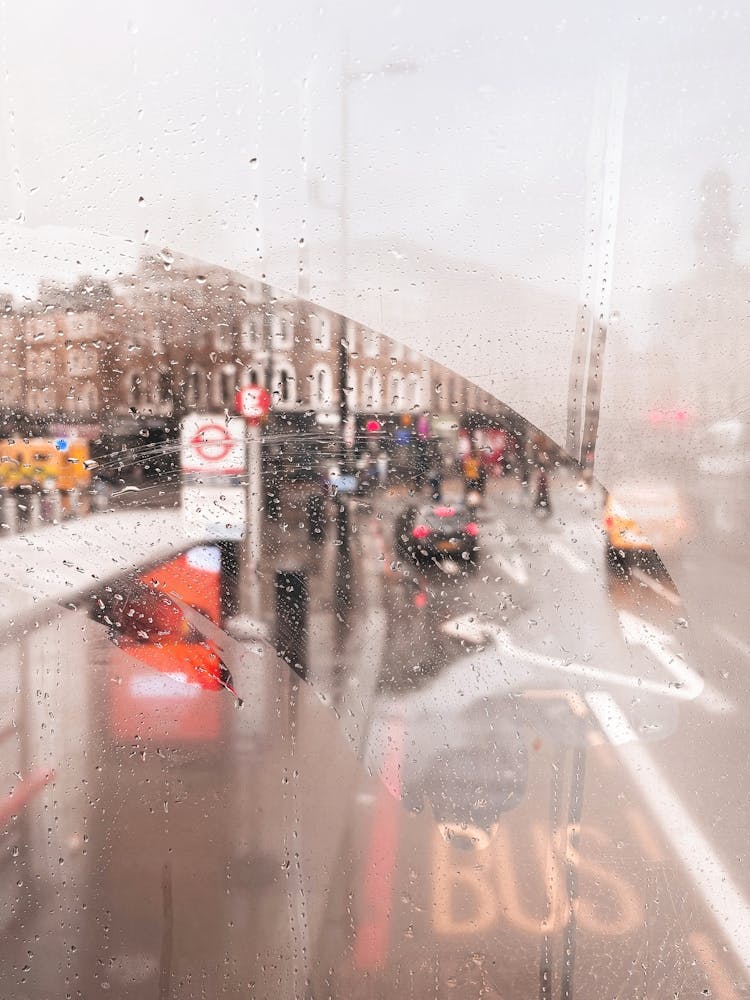 London, England I View of a rainy street through the fogged window of a legendary red London bus capturing nostalgic atmosphere photography and vibrant colors of the city in the rain with grey moody aesthetic