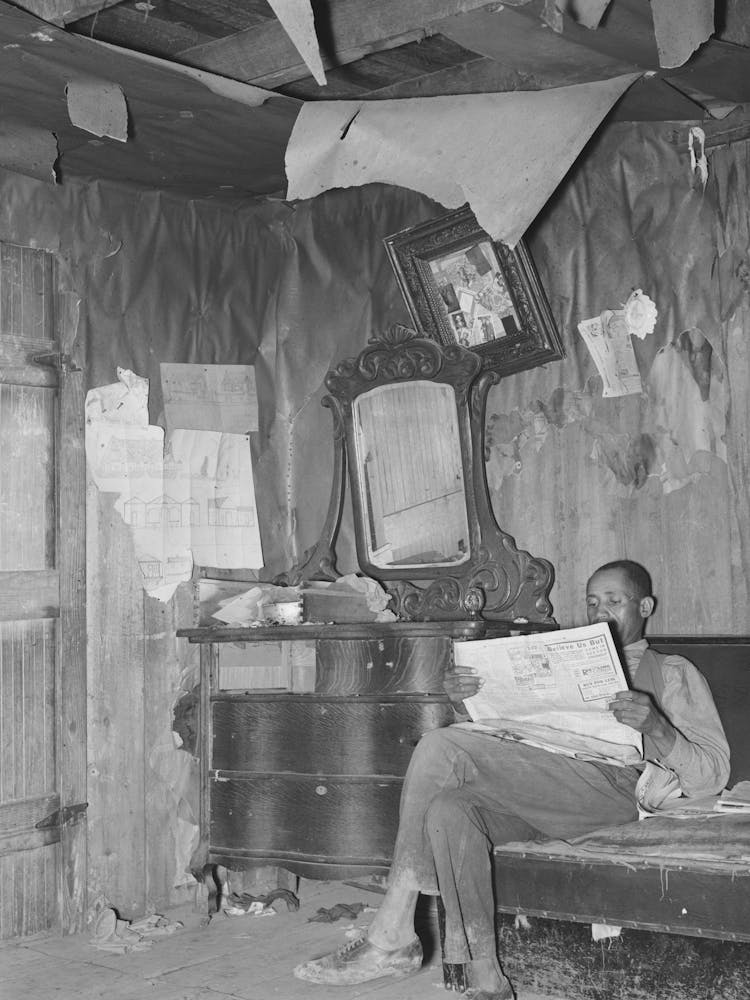Sharecropper Reading Newspaper In Corner Of Living Room, Note The Bureau And Ceiling, Near Southeast Missouri