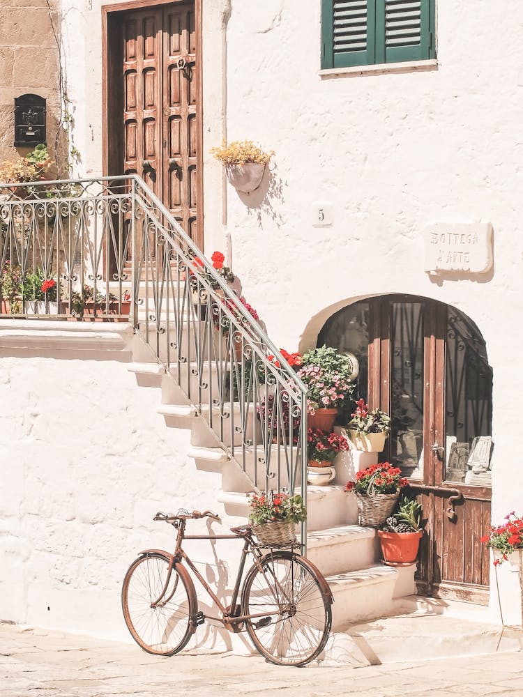 Puglia, Italy I Bicycle in front of flower house in white village of Ostuni in Italian countryside authentic retro vintage minimalist aesthetic photography in pastel Mediterranean summer colors during sunrise