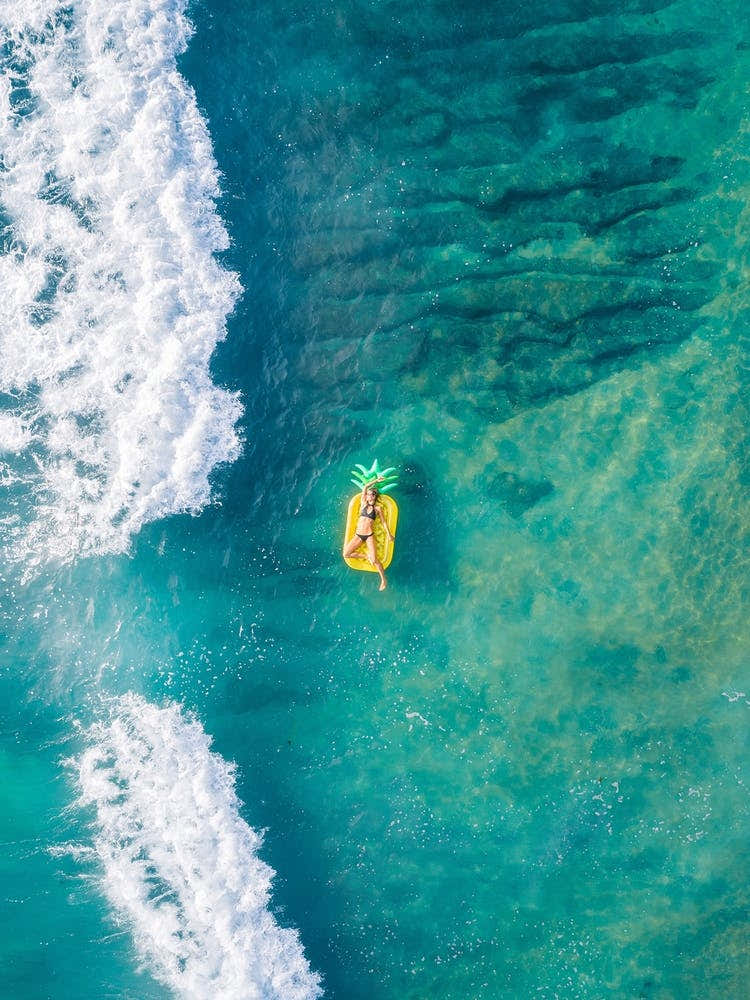 Woman Floating On Pineapple At The Beach
