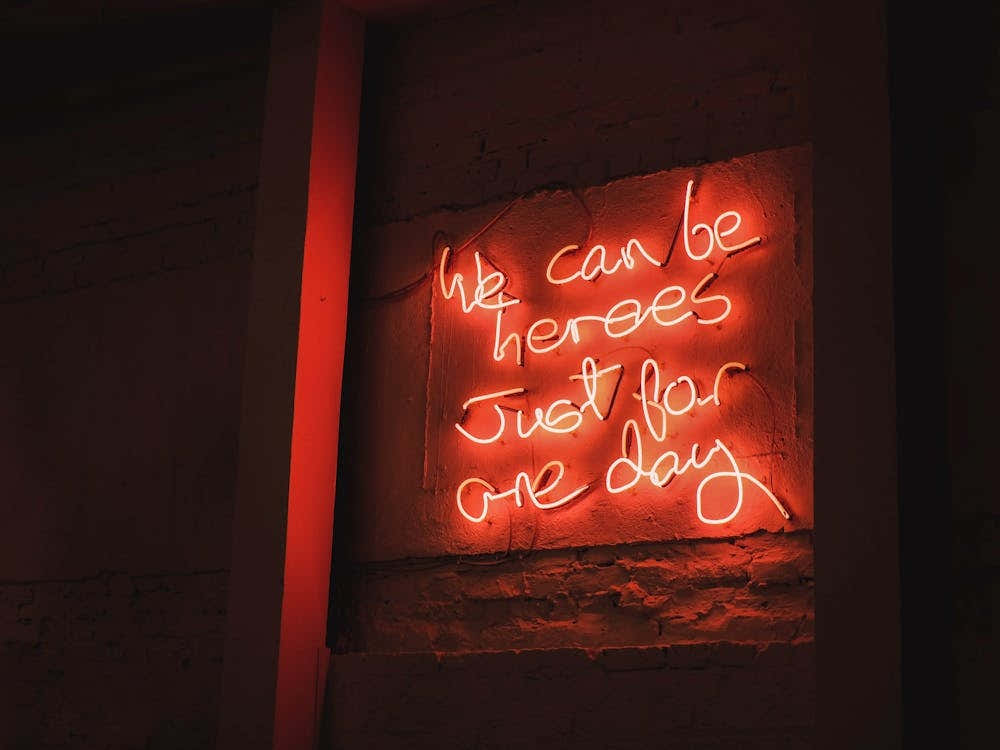 London, England I Vibrant red neon mantra captured in a restaurant window photography with a warm urban ambience with an inspiring phrase about we can be heroes just for one day with a luminous decor light