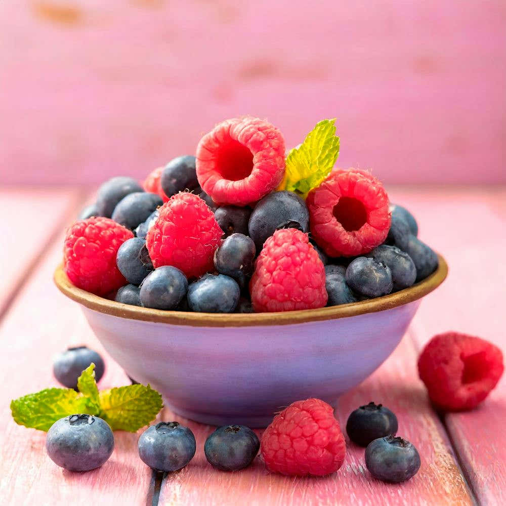A Bowl Fruits With Raspberries And Blueberries On A Rustic Pink Wooden Background