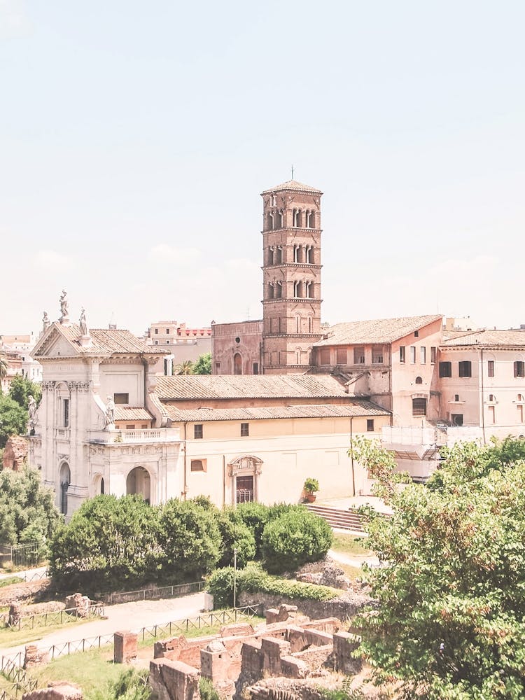 Rome, Italy I Summer skyline panorama view over the Roman Forum with ancient antique architecture and a church nestled in greenery with pastel tones photography and soft light evoking la dolce vita