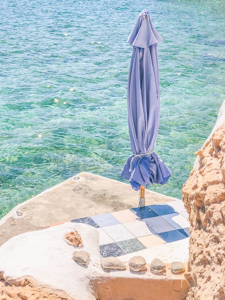 Milos, Greece I Private beach paradise on french riviera in clear blue waters of Mediterranean sea under the summer sun with parasol for minimalist composition of fine art photography pastel aesthetic