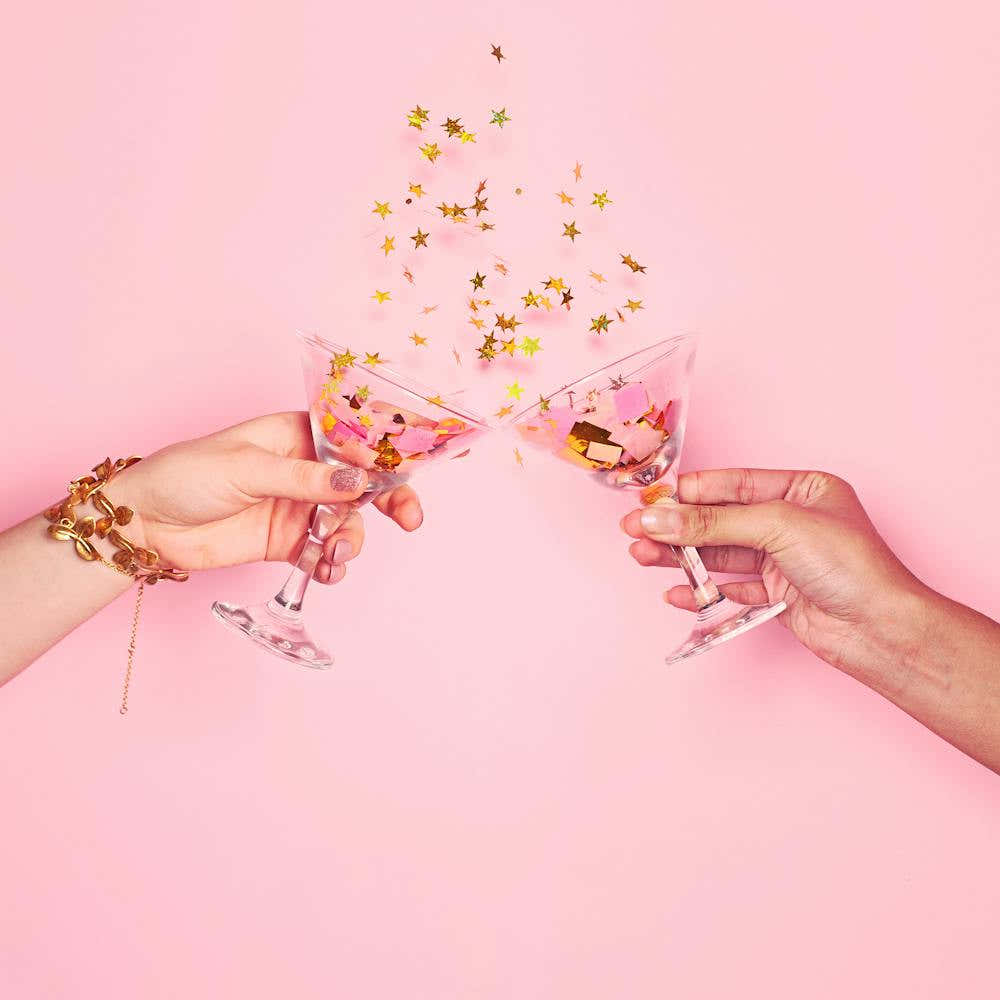 Two Hands Toasting Over Pink Background