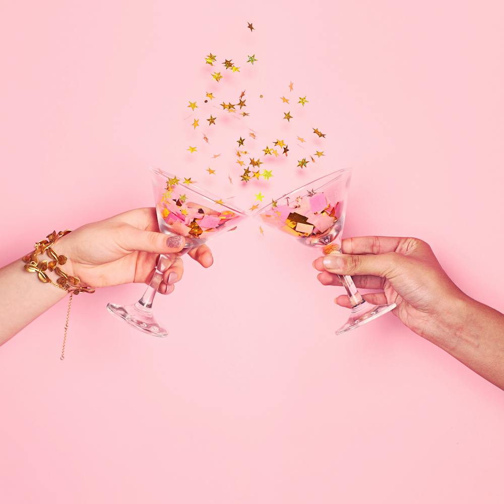 Two Hands Toasting Over Pink Background