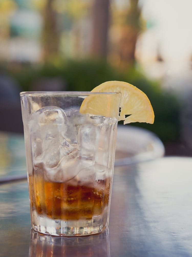 Glass With Cola And Ice And Lemon On A Table Outside