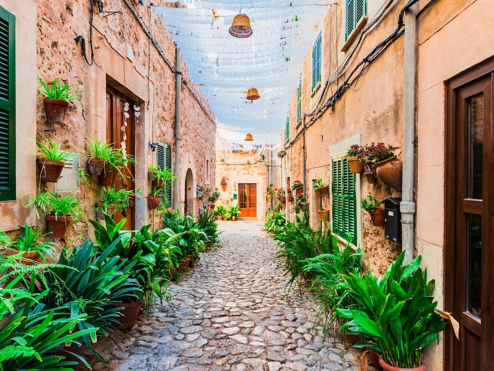 Old village Valldemossa on Mallorca, Spain Balearic islands. This romantic street is a famous landmark that depicts the rich history and Mediterranean culture of the town. The narrow alley is brimming with charming potted plants and flowers, adding to the allure of the picturesque village.