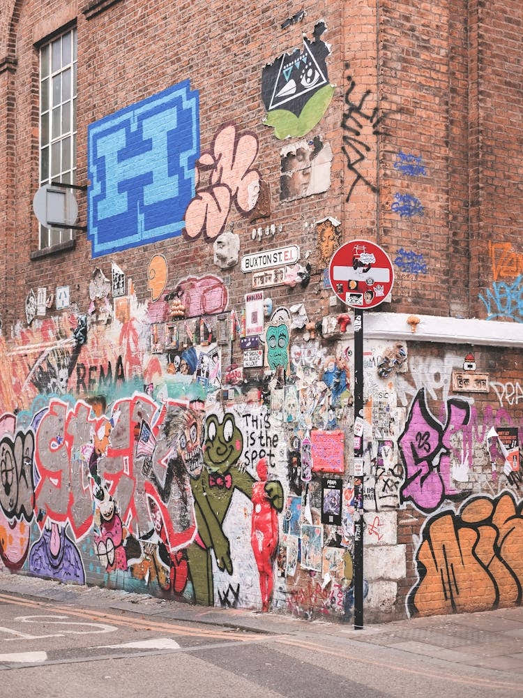 London, England I Colorful retro street art and urban graffiti on brick wall of Shoreditch streets with the industrial architecture and mural design vibrancy of London's suburbs urban exploration photography