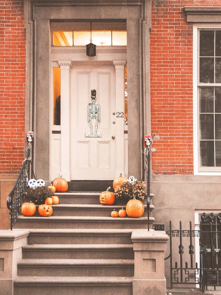 New York, USA I Halloween door in autumn tones with pumpkins and skeleton decoration for a welcoming aesthetic home to brick architecture for an original door photography for interior decor