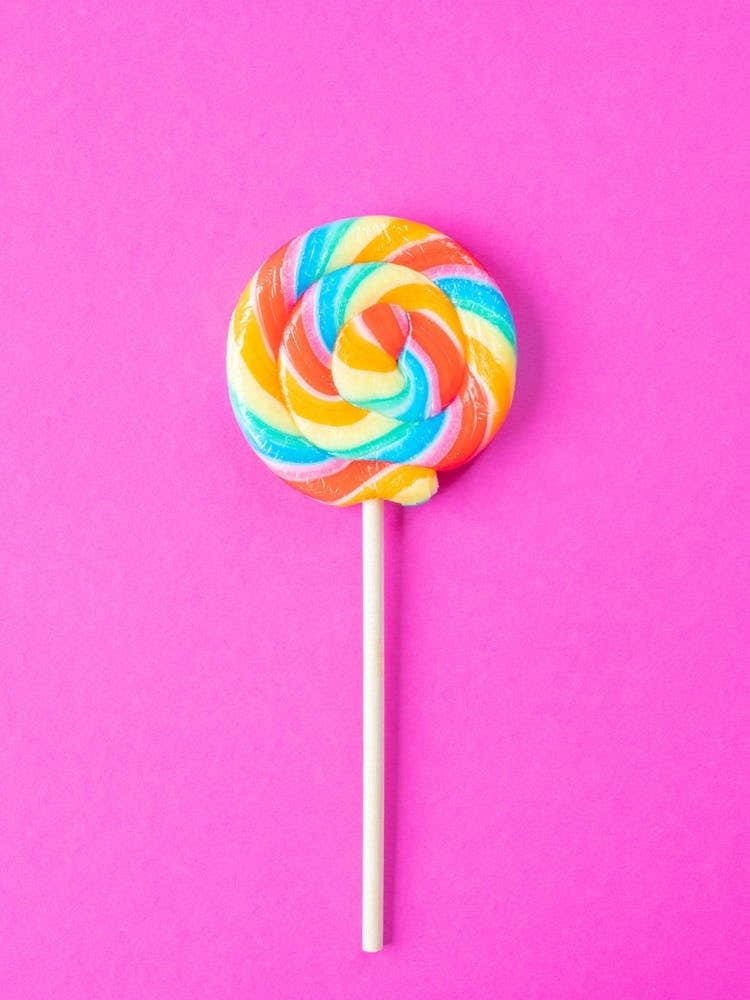 Rainbow colored lolly on a bright pink background - food photography great for a kids room by Christa Stroo Photography