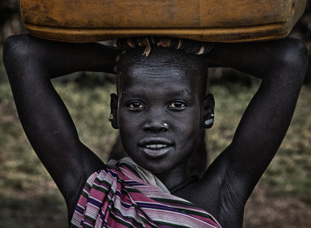 South Sudanian girl carrying a container with water.