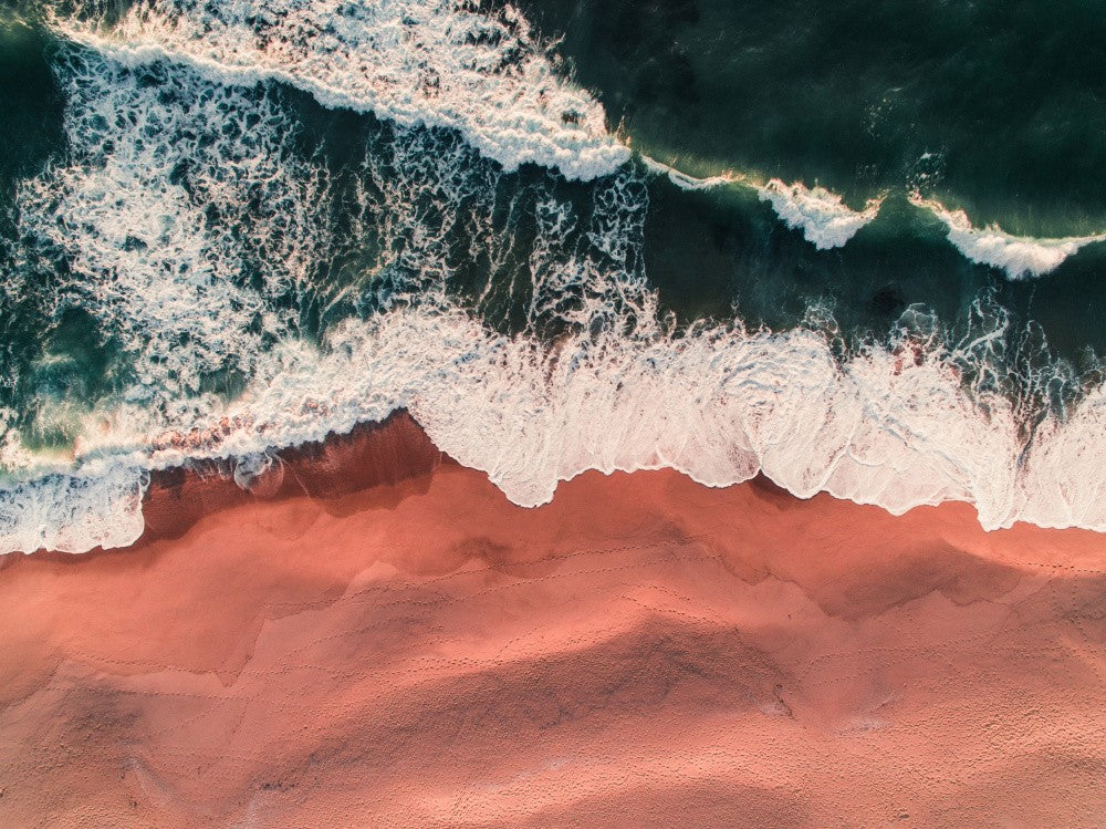 Lebendiger rosa Sand und schaumige türkisgrüne Wellen