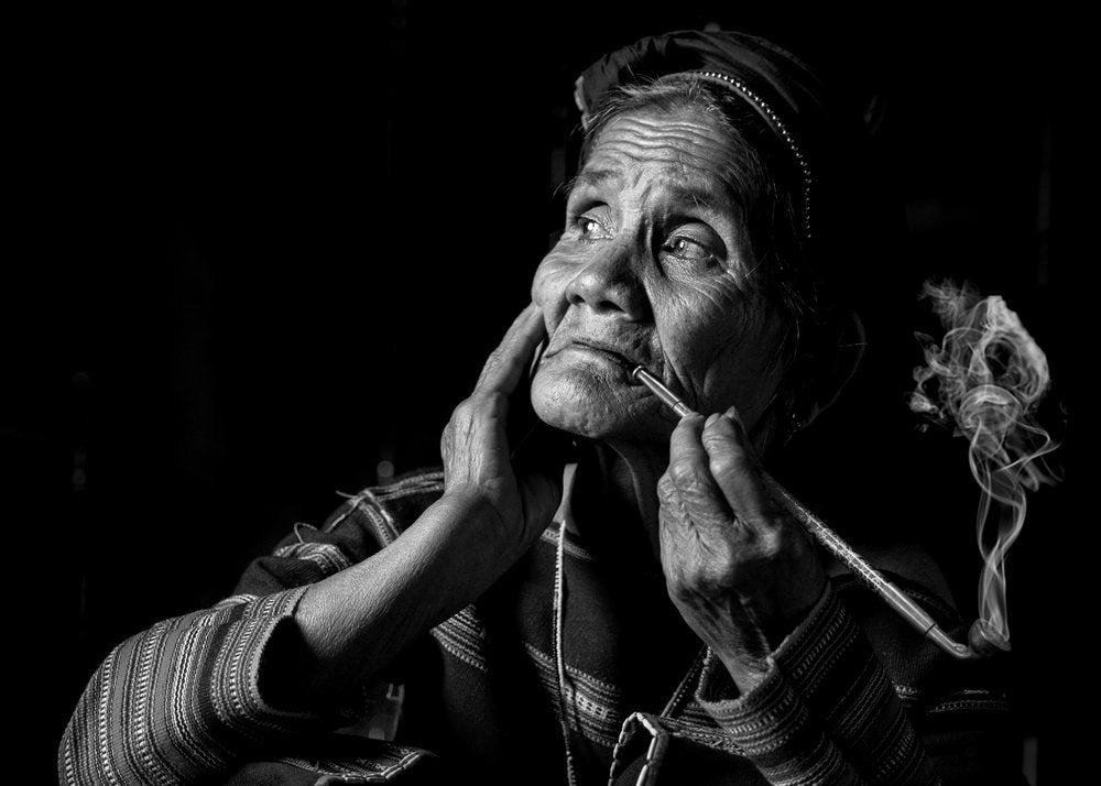 Elderly Woman Smokes Pipe