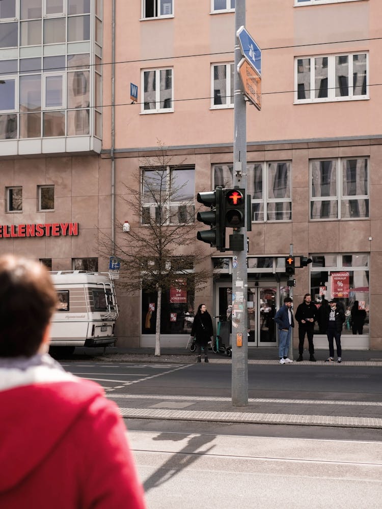 Berlin, Germany I Red Ampelmännchen traffic light with pedestrian at crosswalk in geometric street scene with retro vintage candid urban photography of daily city life and modern Bauhaus architecture