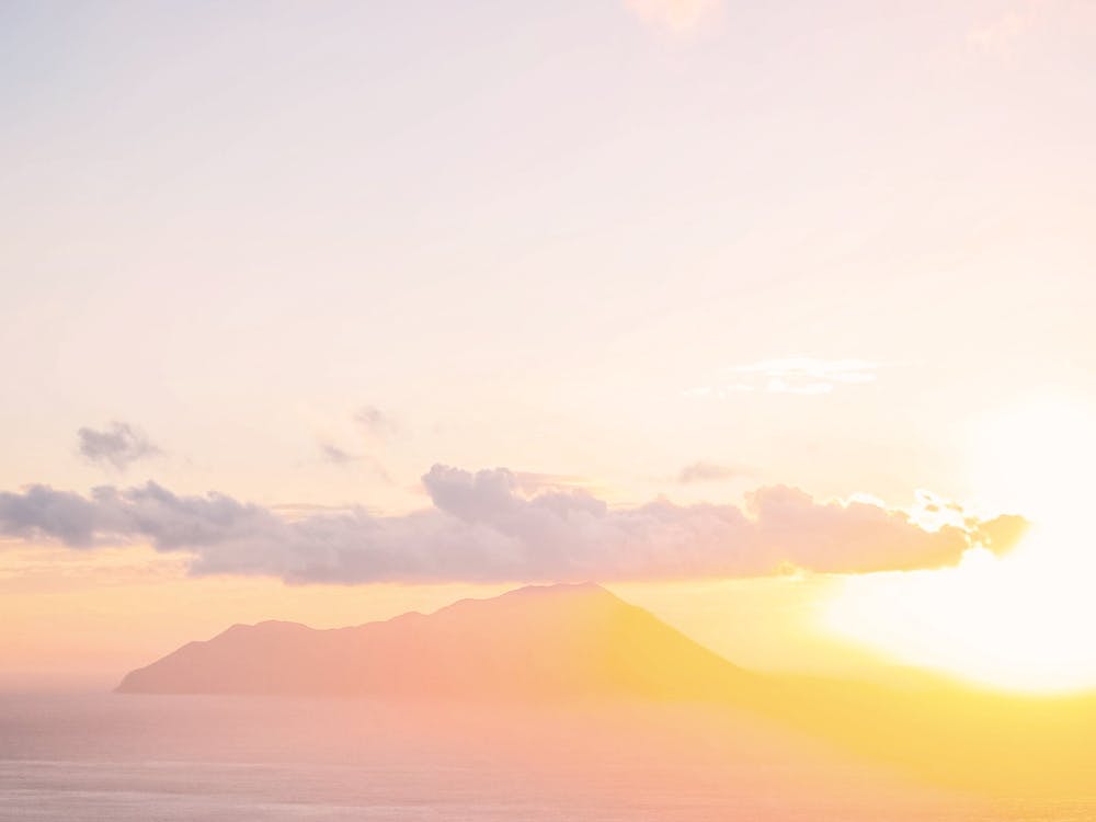 Milos, Greece I Aesthetic orange pastel sunset light over the greek mountains of the Cyclades island from the village of Plaka for a colorful minimalist geometric graphic design fine art photography
