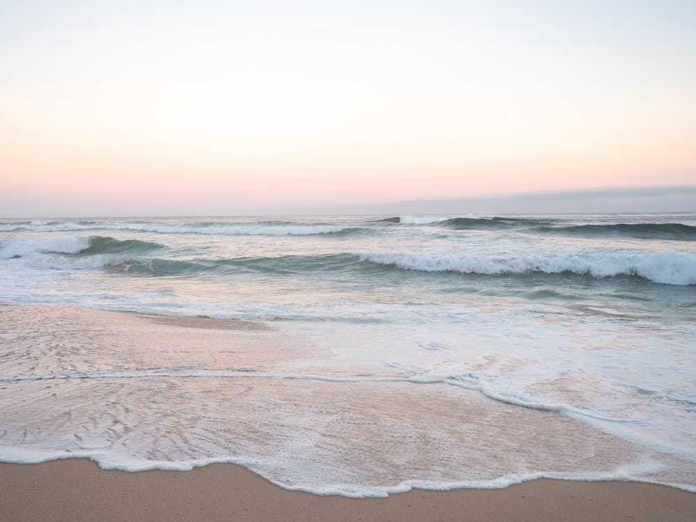 Pastel colors at sunrise. At the beach at Praia da Adraga in Portugal - pink and blue nature and travel photography by Christa Stroo