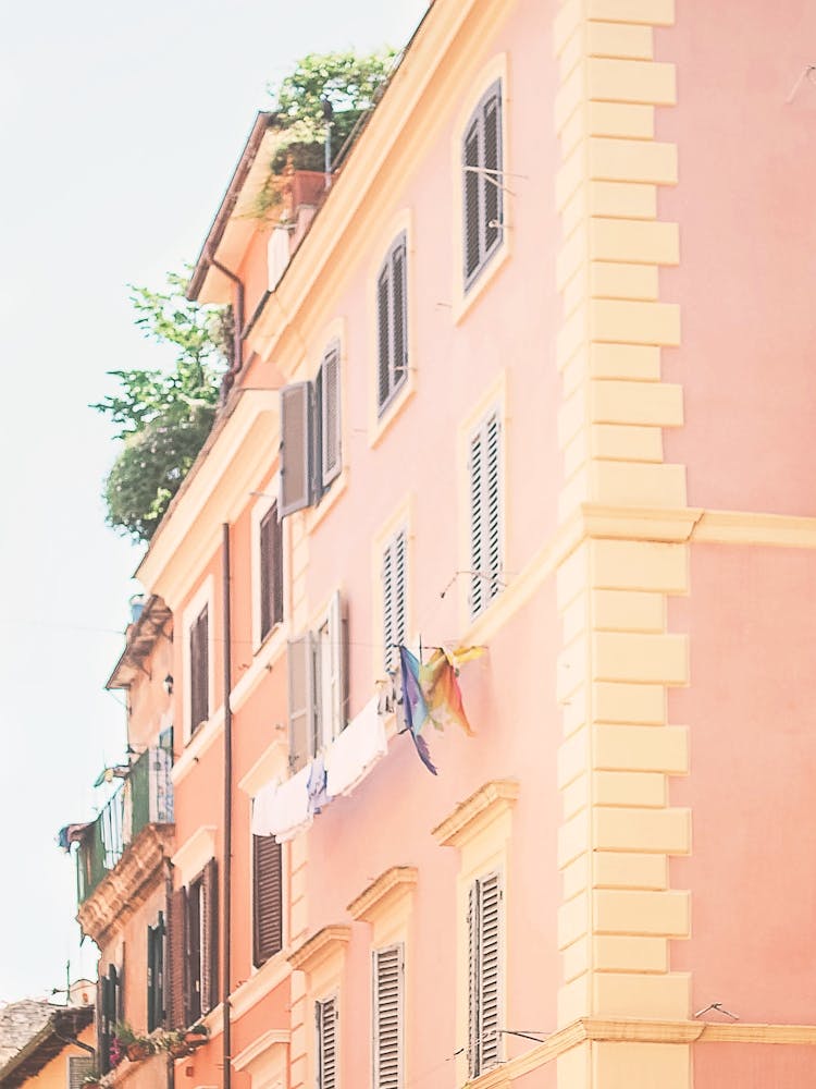 Rome, Italy I Pastel colored orange and pink facade architecture with laundry drying in a minimalist everyday life scene photography capturing the authentic la dolce vita essence of Italian summer