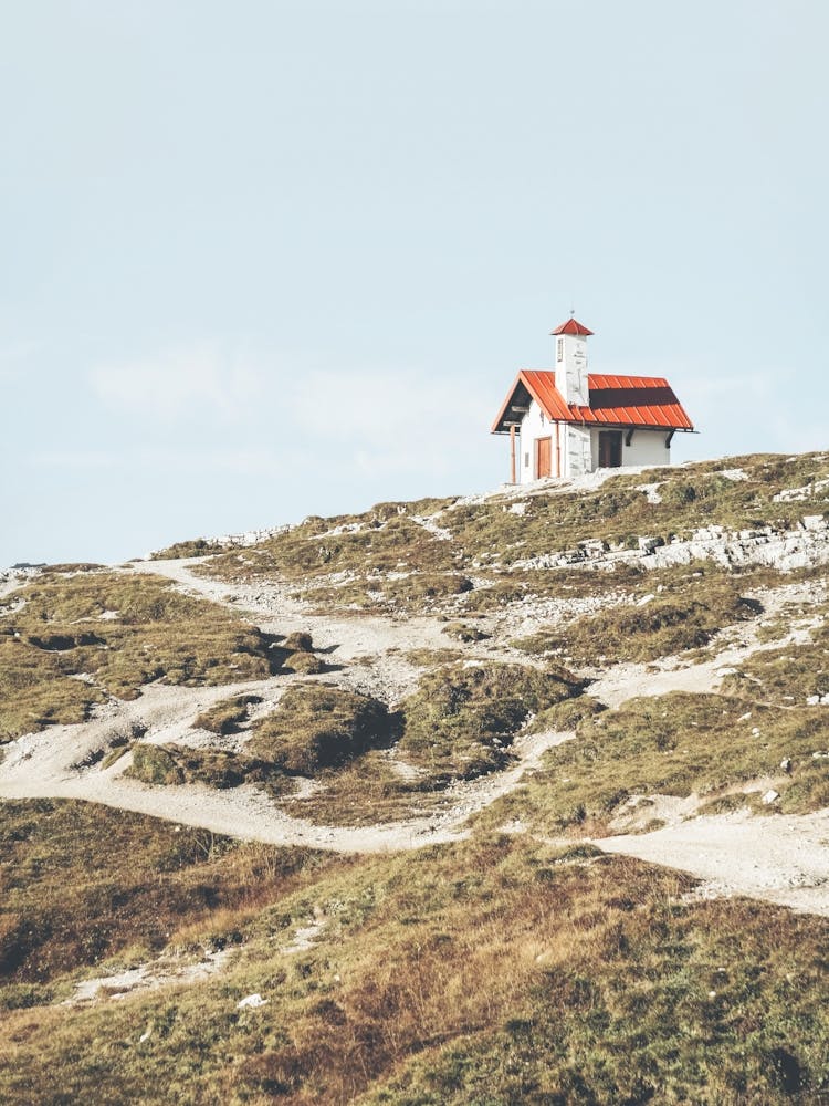 Dolomites, Italy I The little red roof chapel church overlooking the green mountains of the Tre Cime with a retro vintage analog film photography featuring a minimalist geometric design art composition