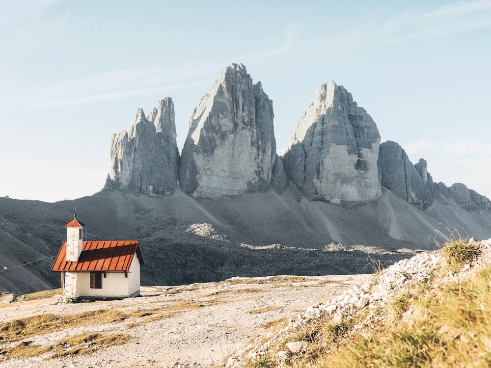 Dolomites, Italy I Isolated church in front of the Alps mountain peaks of the Tre Cime di Lavaredo for a panorama view of an imposing rock nature landscape photography in the pastel soft light of sunrise sunset