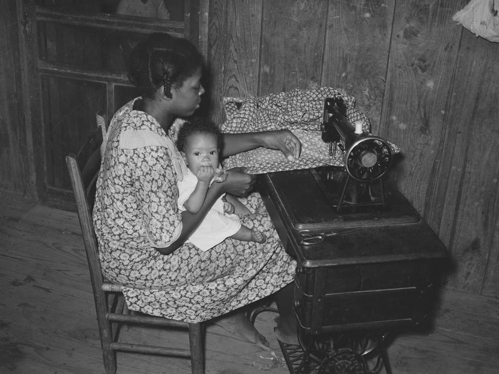 Wife Of Sharecropper, With Baby In Her Lap, At Sewing Machine, Family Will Work Under Tenant Purchase Program