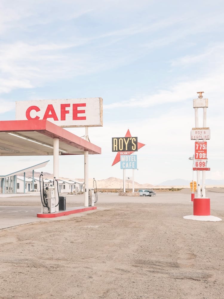 Route 66, USA I Mythical historic Roy's Cafe and Motel gas station in a California desert landscape photography in an American retro vintage american countryside with summer light pastel red and blue aesthetic