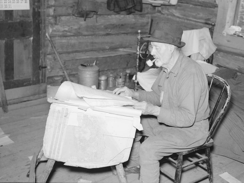 William Besson, Iron Ore Prospector, Examining Geological Survey Maps In His Cabin Near Winton, Minnesota By Russ