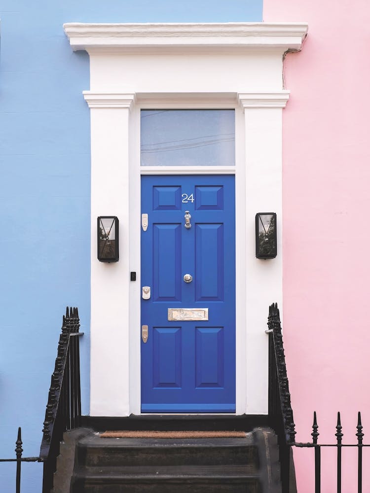 London, England I Sinnbildliche blaue Tür eines Pastellhauses in Notting Hill mit seiner rosa-blauen Fassade zur klassischen viktorianischen minimalistischen geometrischen farbenfrohen Londoner Architekturfotografie einer urbanen Straßenlandschaft