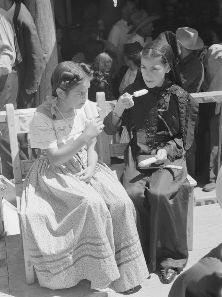 Two Spanish American Girls Dressed In Fiesta Costumes Eating Popsicles, Taos, New Mexico By Russell Lee