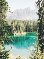 Dolomites, Italy I Lago di Carezza alpine lake with blue turquoise waters, fir forests and mountains for a unique natural alpine landscape photography with a pastel aesthetic similar to that of Canada or Norway