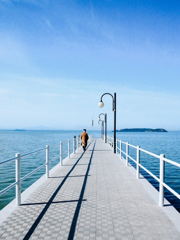 Person Walking On Sunlit Pier 17077792