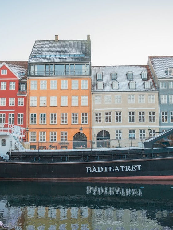 Winter in Nyhavn in Copenhagen, Denmark - snow on rooftops and ships docked in the city harbour - vintage travel photography by Christa Stroo Photography