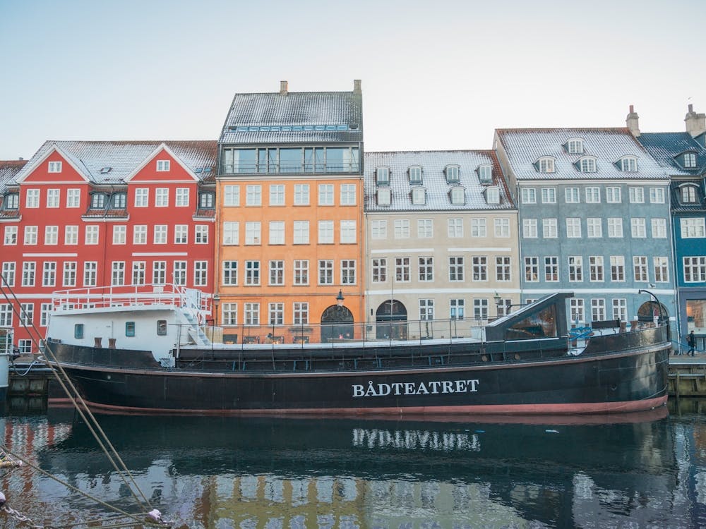 Winter in Nyhavn in Copenhagen, Denmark - snow on rooftops and ships docked in the city harbour - vintage travel photography by Christa Stroo Photography