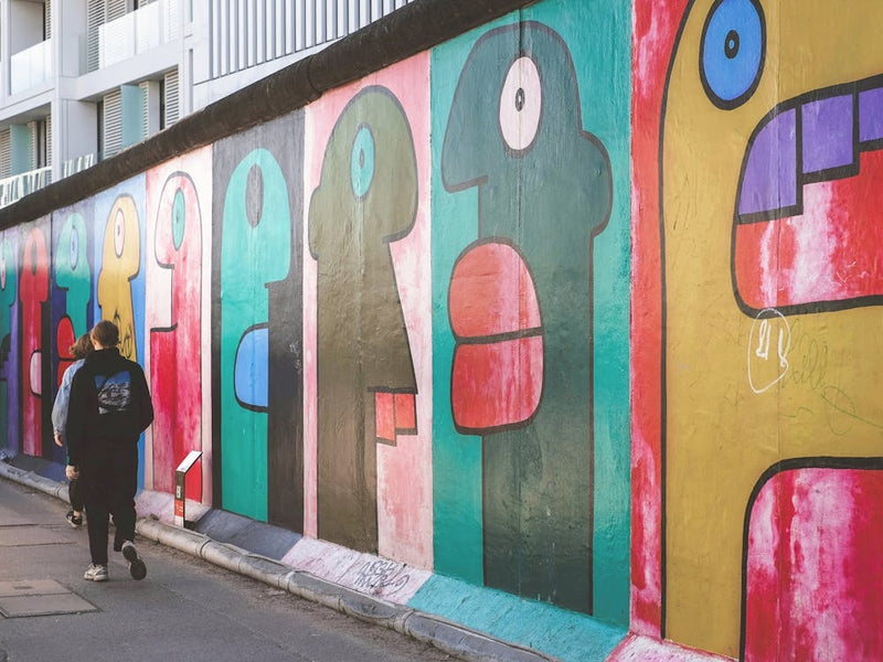 Berlin, Germany I Berlin Wall street art with colorful mural and people walking capturing a vibrant urban street scene photography full of graphic pop art graffiti energy and alternative city vibes