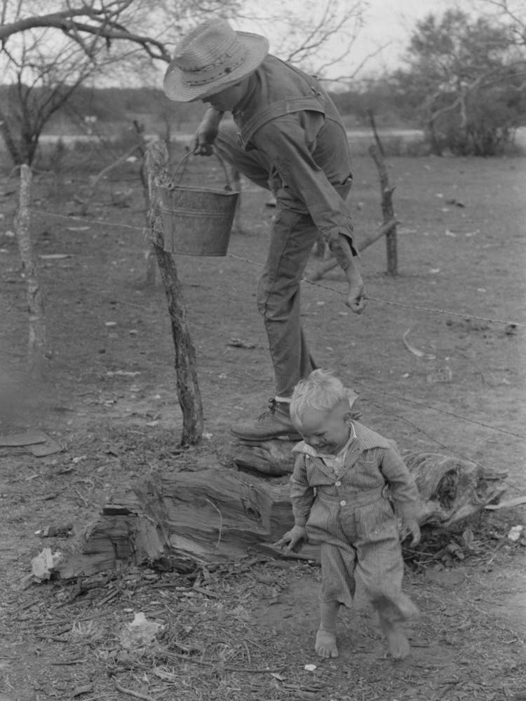 Child Of White Migrant Climbing Fence With Pail Of Water Near Harlingen, Texas By Russell Lee
