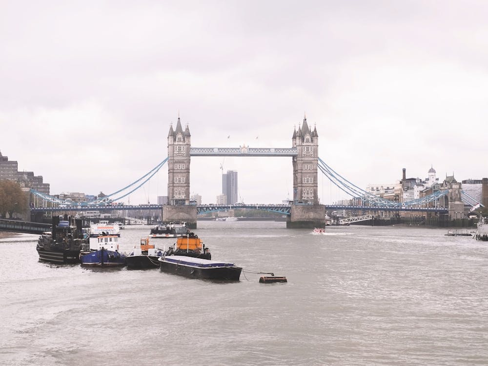 London, England I Grey panoramic skyline view photography of the famous Tower Bridge and the River Thames to the Victorian architecture and British charm of an urban city landscape under rainy weather