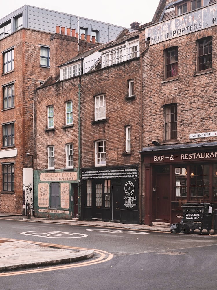 London, England I Street with brick architecture facades in Londoner vintage district of Spitafields from a retro UK urban landscape to the dark moody aesthetic of an analog film photography