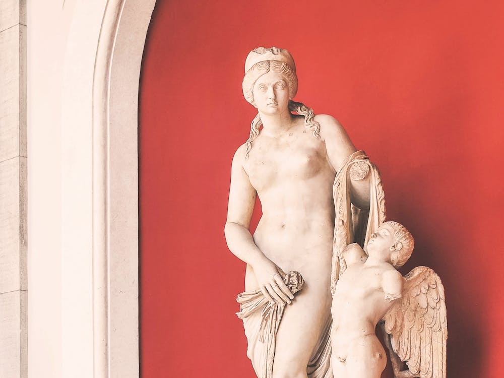 Rome, Italy I Minimalist antique angels statues against vibrant red wall in Vatican Museum or Louvre with artistic photography in pastel aesthetic evoking Roman history and elegant summer la dolce vita