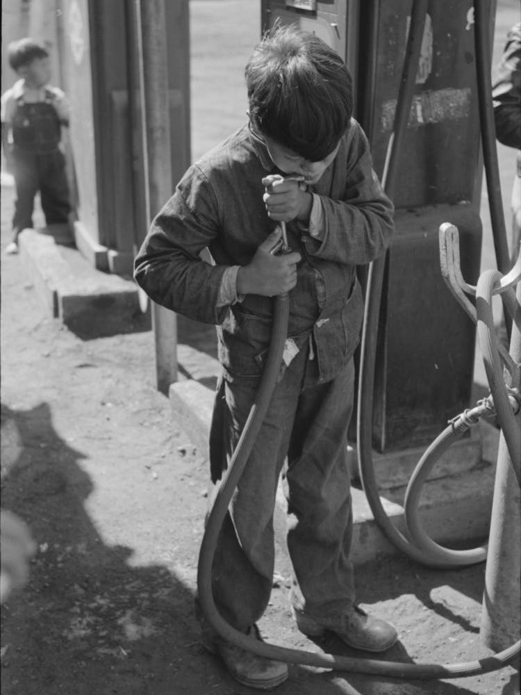 Mexican Migrant Boy Drinking Out Of Water Hose At Filling Station Where The Truck Which Is Taking Him Home From