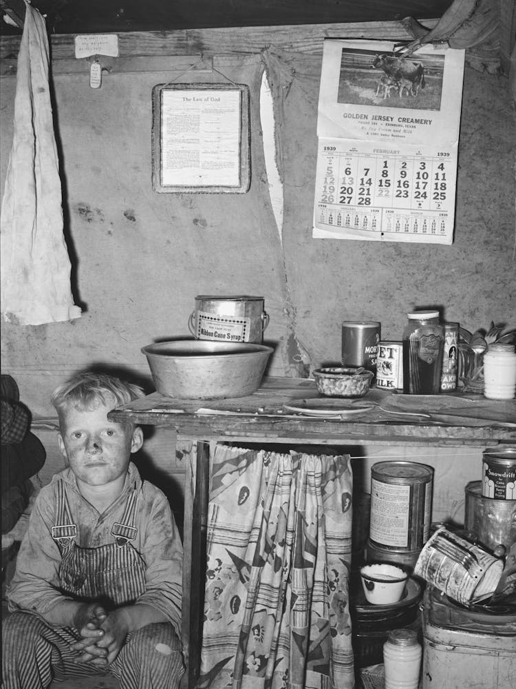 Child Of Migrant Sitting By Kitchen Cabinet In Tent Home Near Edinburg, Texas By Russell Lee