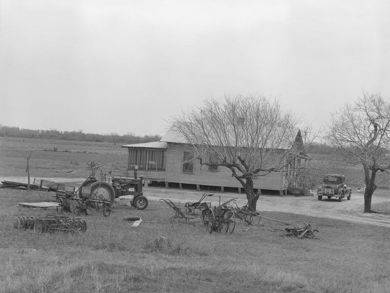 Farmhouse Of Small Farmer Near Santa Rosa, Texas, Tractor And Rusting Farm Implements Are In The Yard, Showing