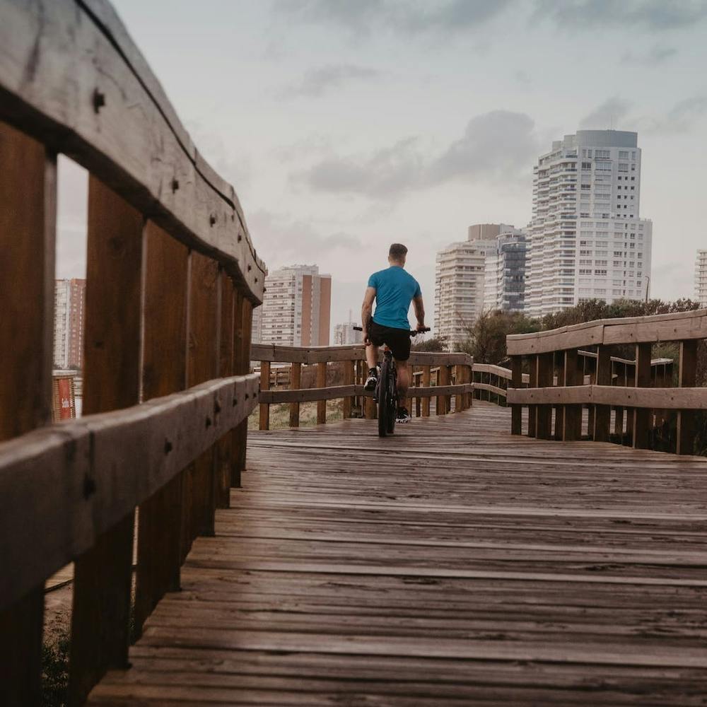 Man Riding Bike On Wooden Boardwalk