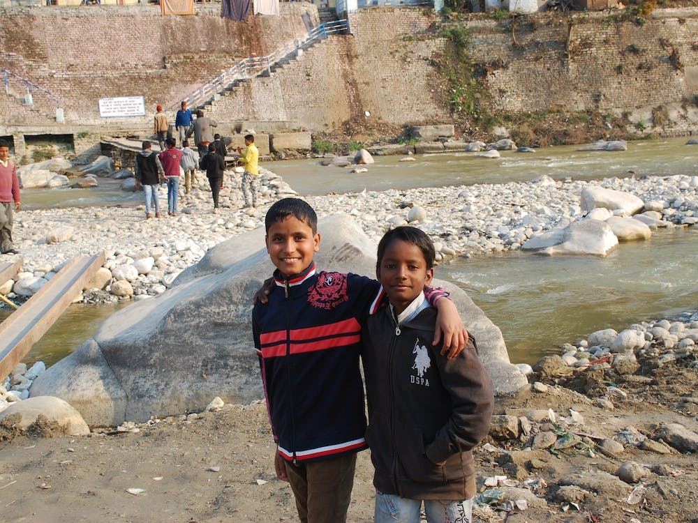 Two Children Standing In Front Of A River