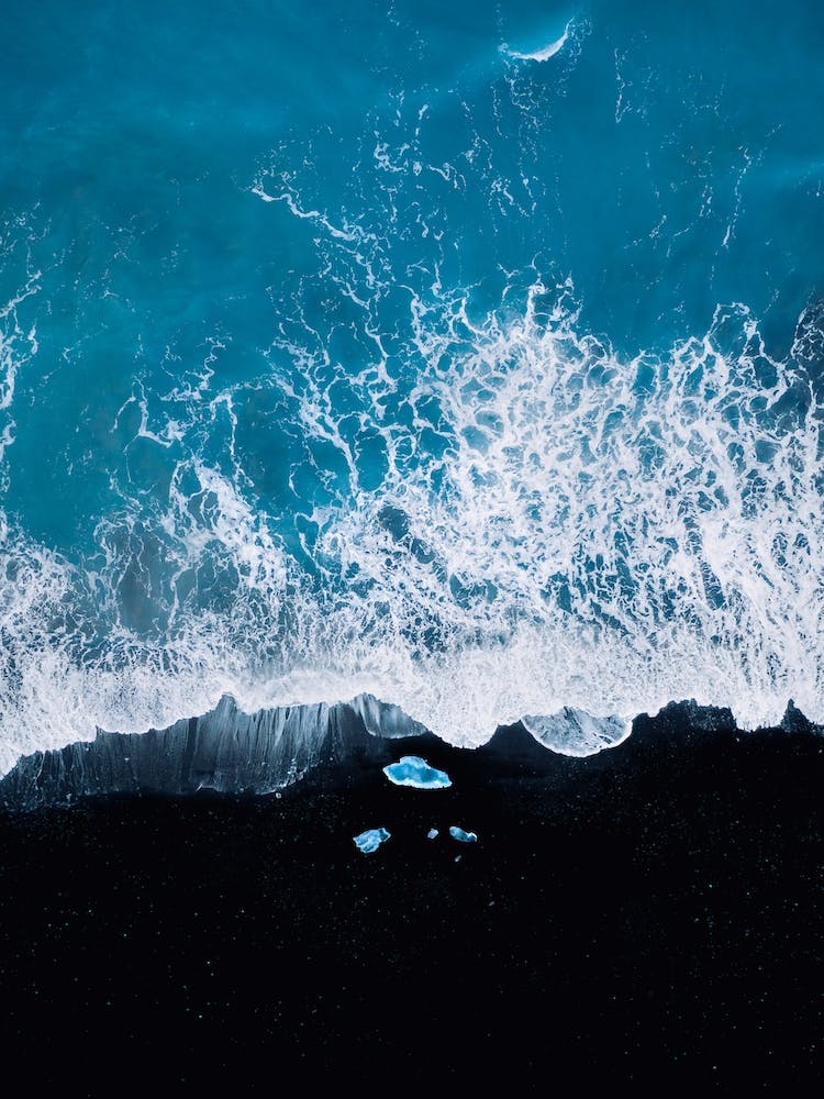 Black Sand Beach In Iceland With Waves And Ice