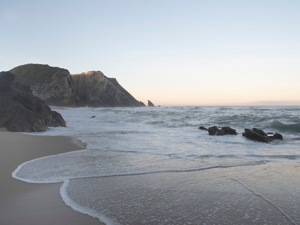 Quiet sunrise at Praia da Adraga beach in summer in Portugal - Pastel colors travel photography by Christa Stroo Photography