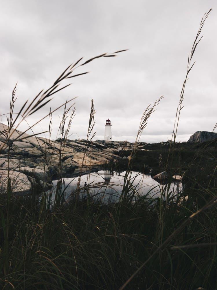 Peggys Cove Lighthouse in Nova Scotia With Pond Mirroring The Lighthouse