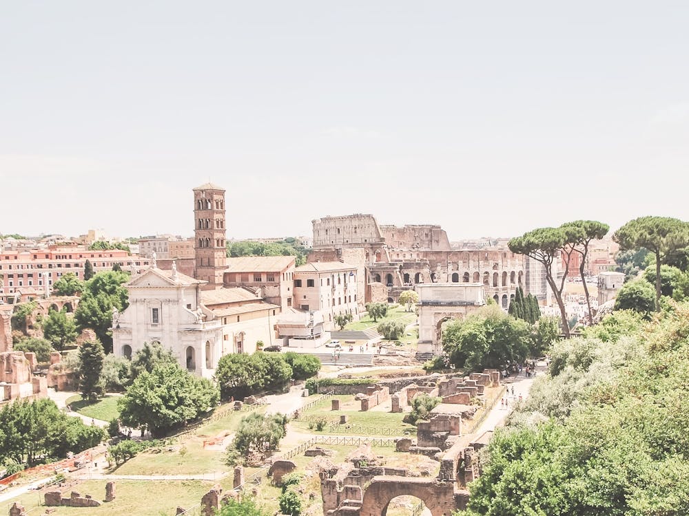 Rome, Italy I Panoramic view of the Roman Forum with the Colosseum and italian ancient ruins glowing in soft pastel summer aesthetic light for a retro vintage la dolce vita atmosphere photography
