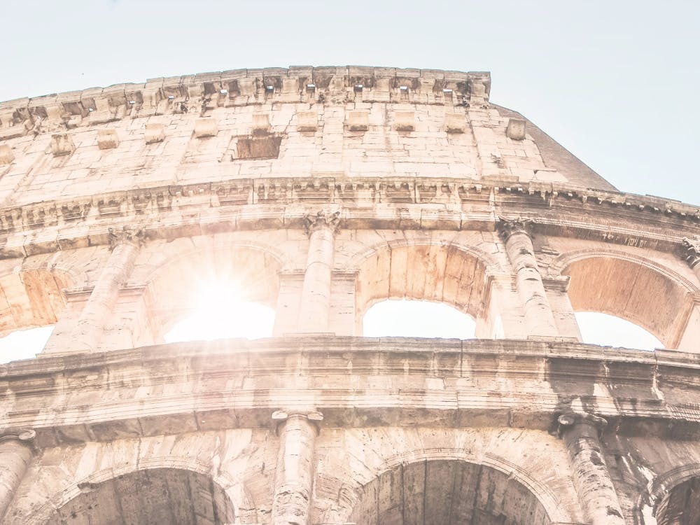 Rome, Italie I Vue du Colisée avec la lumière du soleil estivale à l'esthétique pastel traversant les arches pour une architecture géométrique minimaliste et une atmosphère estivale avec une photographie majestueuse du patrimoine romain